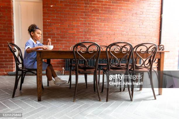 a young girl sitting alone at her dining table eating breakfast - melbourne school stock pictures, royalty-free photos & images