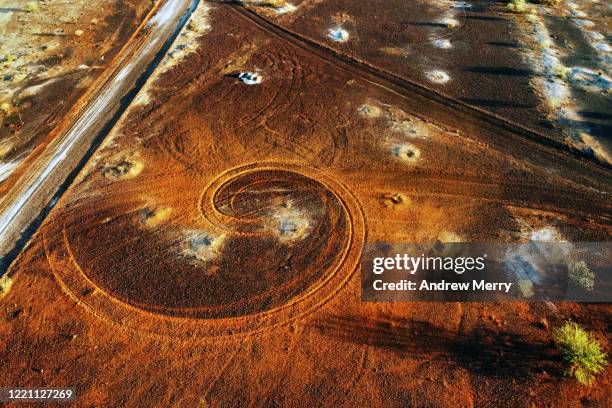 abstract swirl pattern from car tyre tracks in red dirt, illuminated by dusk sunlight, remote rural australia - opal mining stock pictures, royalty-free photos & images