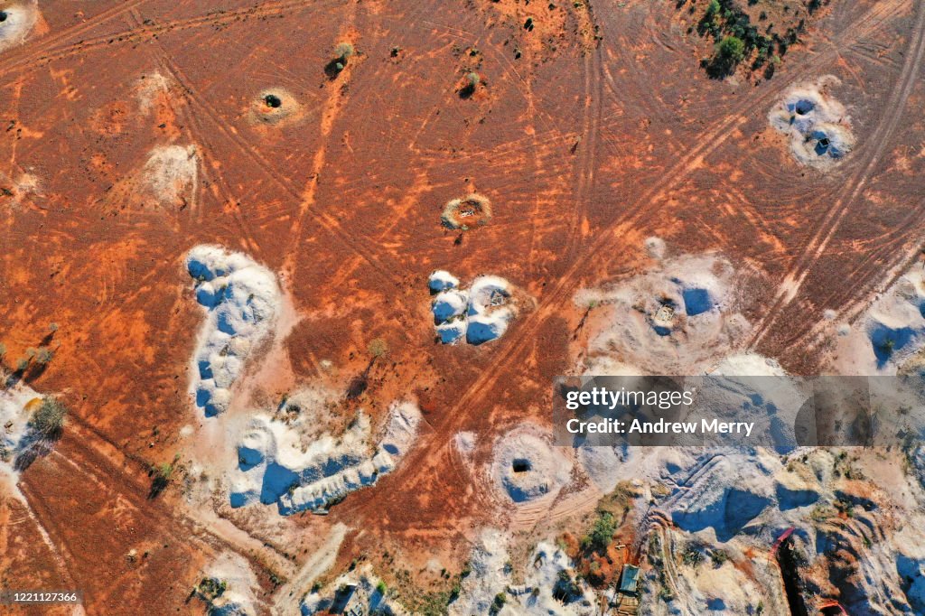 Desert landscape with mineshaft holes, white dirt mine tailings on red earth, White Cliffs, Australia