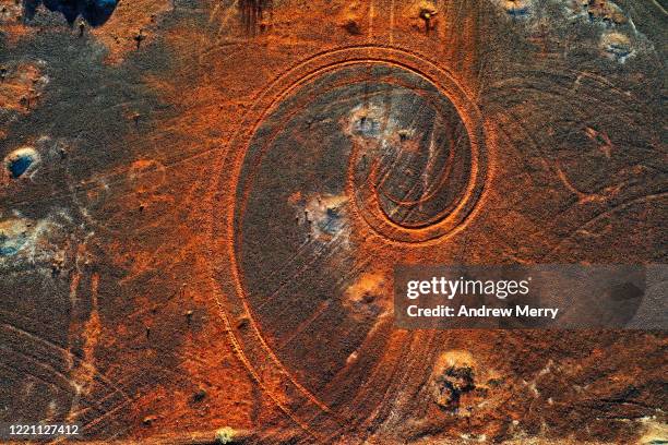 abstract swirl pattern from car tyre tracks in red dirt, illuminated by dusk sunlight, remote rural australia - earth mover fotografías e imágenes de stock