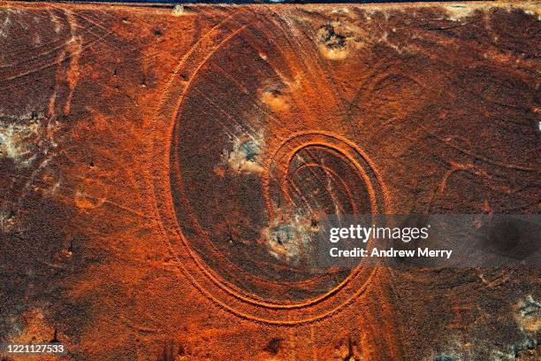 abstract swirl pattern from car tyre tracks in red dirt, illuminated by dusk sunlight, remote rural australia - red dirt stock pictures, royalty-free photos & images