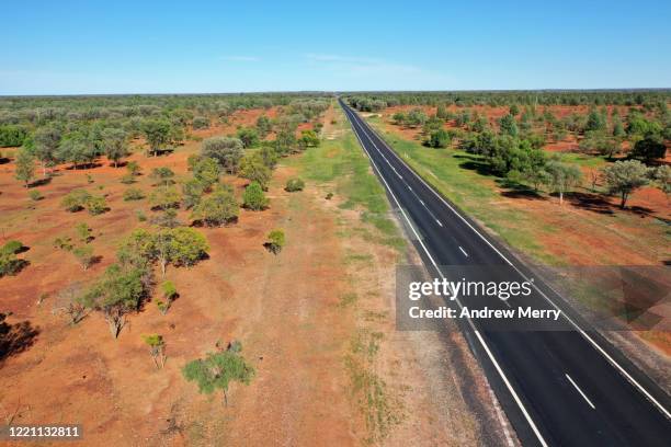 highway, road through semi-arid landscape with red dirt and blue sky, road trip in australia - country road australia stockfoto's en -beelden