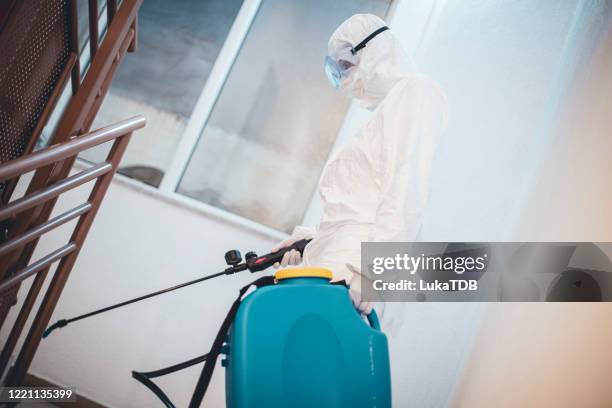 une femme dans la combinaison protectrice désinfectant l’espace résidentiel de bâtiment - fumigation photos et images de collection
