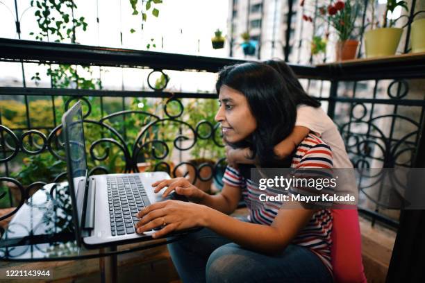 daughter hugs mother while working on laptop in the balcony - woman home with sick children imagens e fotografias de stock