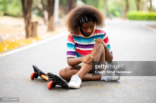 injured skater on road at the skateboard park. african girl sitting on road after skateboard accident. - broken skateboard stockfoto's en -beelden
