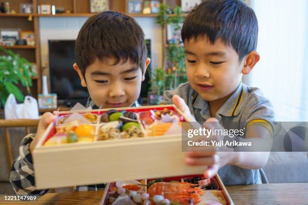 two boys looking at osechi, japanese traditional new years dish - osechi ryori stock pictures, royalty-free photos & images