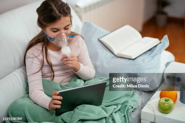 pequeña niña en la cama con inhalador foto de archivo. - traquea fotografías e imágenes de stock