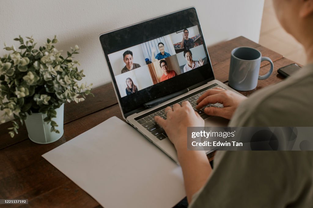 Eine asiatische Chinesin, die zu Hause mit Laptop-Videokonferenz-Telefonkonferenz arbeitet