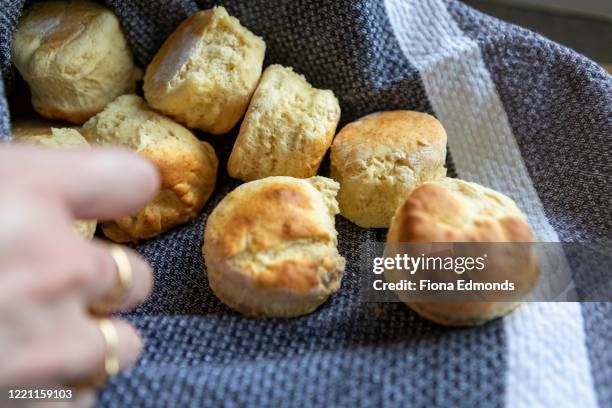 batch of freshly baked warm scones in grey and white striped tea towel - scone - fotografias e filmes do acervo