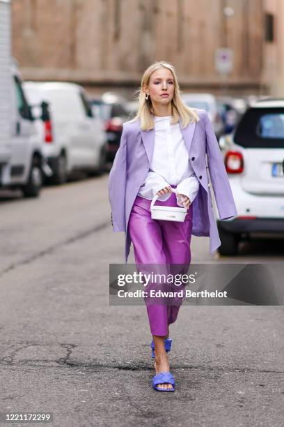 Leonie Hanne wears a mauve oversized blazer jacket, a white shirt, a white bag from Jacquemus, purple leather cropped pants, blue quilted sandals,...