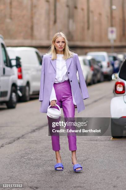 Leonie Hanne wears a mauve oversized blazer jacket, a white shirt, a white bag from Jacquemus, purple leather cropped pants, blue quilted sandals,...