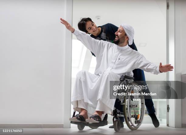 arabic happy man in wheelchair at home - man wheel chair stock pictures, royalty-free photos & images