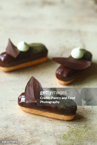 traditional french eclairs filled with matcha tea pastry cream and topped with chocolate glaze - eclair stock pictures, royalty-free photos & images