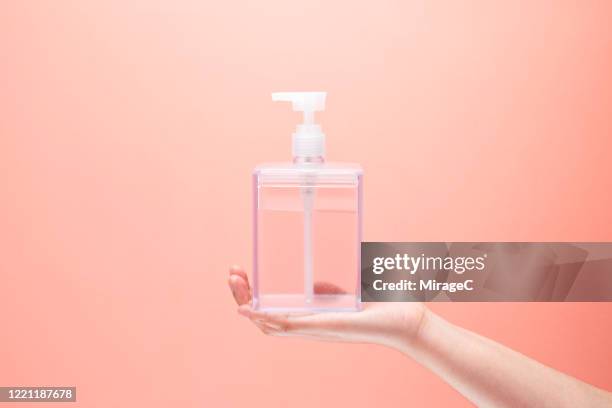 hand holding soap dispenser - shampoo stock-fotos und bilder