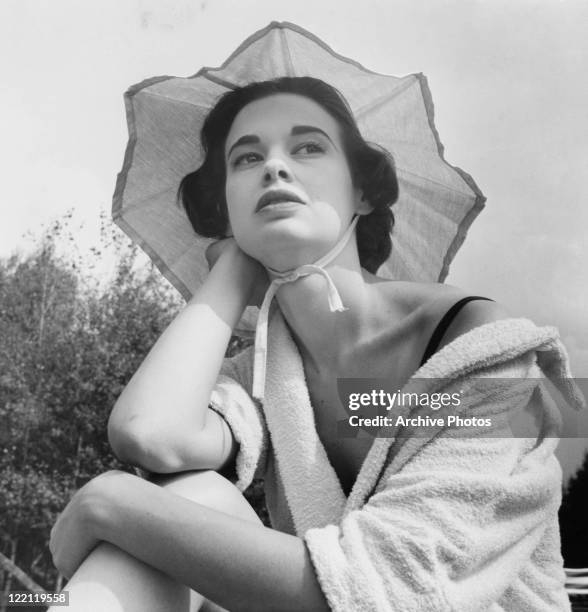 American socialite, fashion designer, actress, writer and artist Gloria Vanderbilt wearing a towelling robe, August 1954.