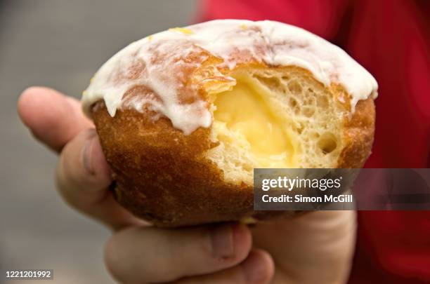 man's hand holding a lemon filled doughnut with missing bite - bite mark stock pictures, royalty-free photos & images