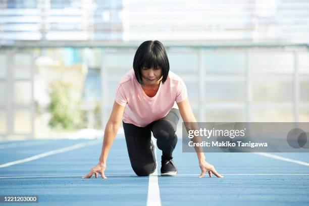 mature japanese sportswoman in starting position - woman starting line stock pictures, royalty-free photos & images