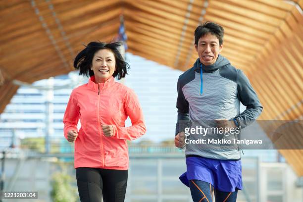 mature japanese sportsman and sportswoman running on track - asian man exercise stock pictures, royalty-free photos & images