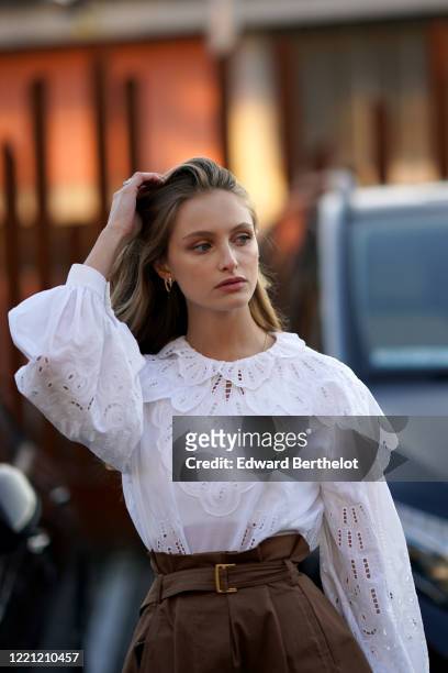Beatrice Vendramin wears a white ruffled lace top with puff shoulders, earrings, outside Alberta Ferretti, during Milan Fashion Week Fall/Winter...