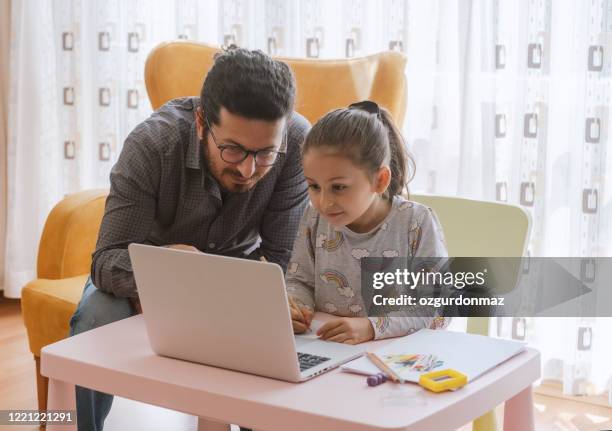 bambina con padre homeschooling e apprendimento a distanza a casa - famiglia multimediale foto e immagini stock