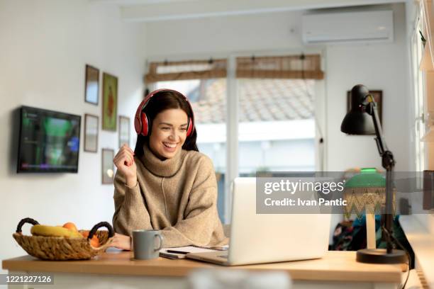 happy young woman working from home on a laptop - mentoring virtual stock pictures, royalty-free photos & images