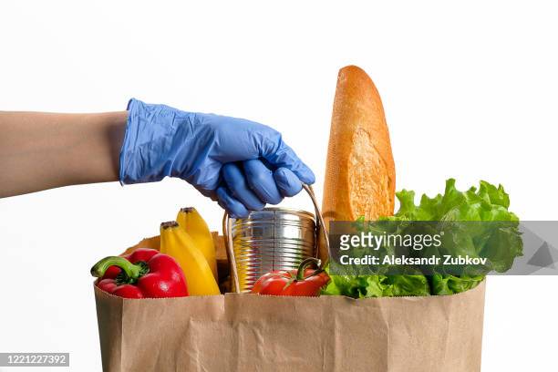in the person's hand is a paper bag with food. donation and home delivery. - glove imagens e fotografias de stock