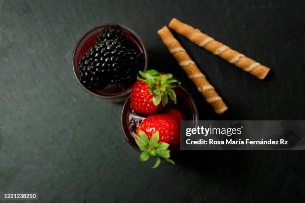 high angle view of homemade fruits of the forest mousse with ripe strawberries and blueberries over slate rock background and copy space. - slate rock stock-fotos und bilder