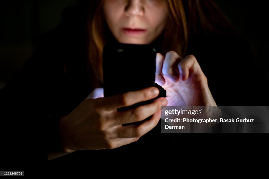 A woman using mobile phone at night, text / online messaging.