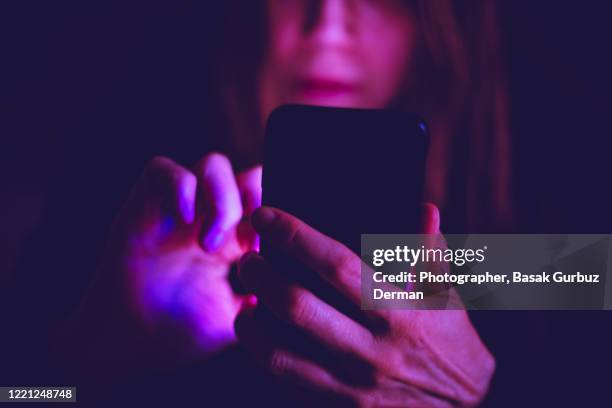 a woman using mobile phone at night, under colorful led lights at a pub / bar - stay home stock pictures, royalty-free photos & images