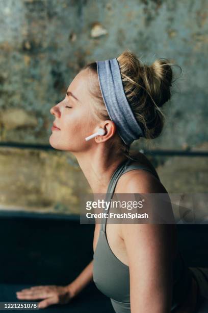 beautiful blonde woman in sportswear listening to music while exercising at home - woman smiling eyes closed stock pictures, royalty-free photos & images