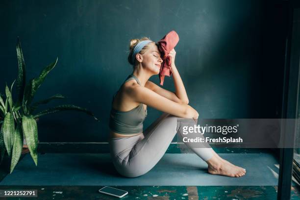 tired, but happy: fit blonde woman wiping her face with a towel after a home workout - towel stock pictures, royalty-free photos & images