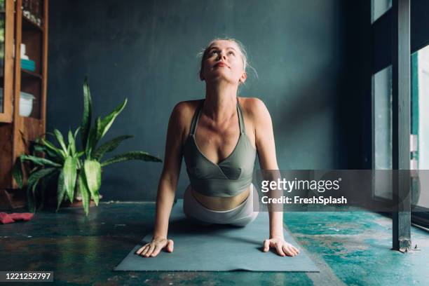 exercising at home: beautiful fit blonde woman doing yoga at home - cobra stock pictures, royalty-free photos & images