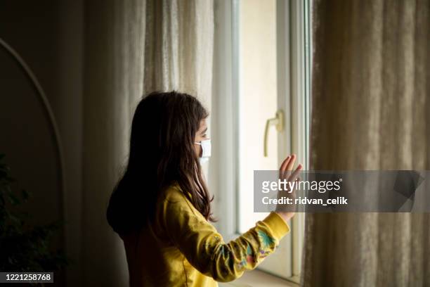 little girl wearing anti virus mask staying at home - pandemic loneliness stock pictures, royalty-free photos & images