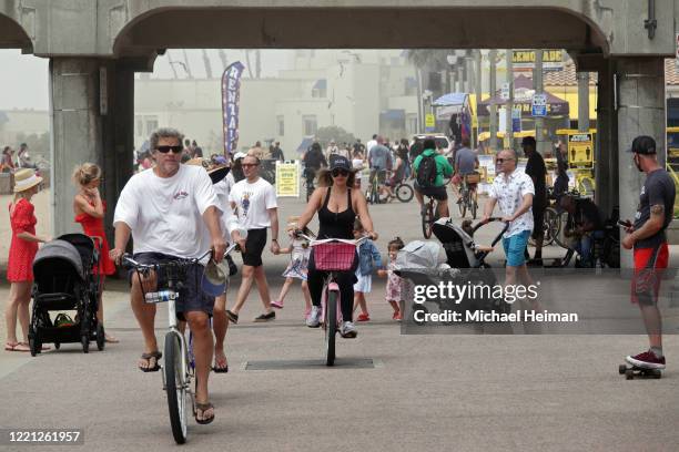 People ride bikes and walk on a path along the beach on April 26, 2020 in Huntington Beach, California. Southern California is expecting summer-like...