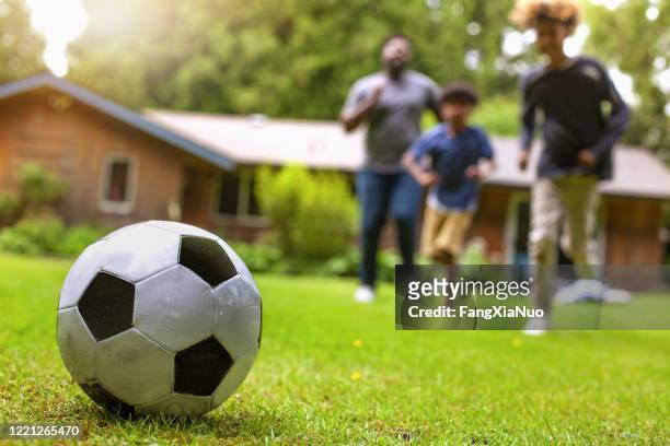 vater und zwei söhne spielen fußball im hinterhof der ferienvilla - backyard football stock-fotos und bilder