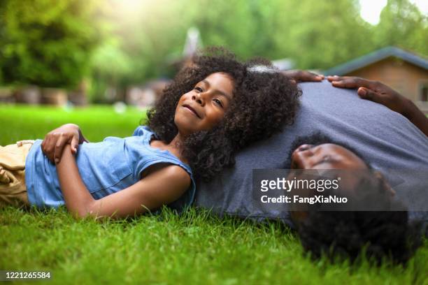afrikaans-amerikaanse zoon en vader rust op gras bij achtertuin vakantievilla - family backyard stockfoto's en -beelden