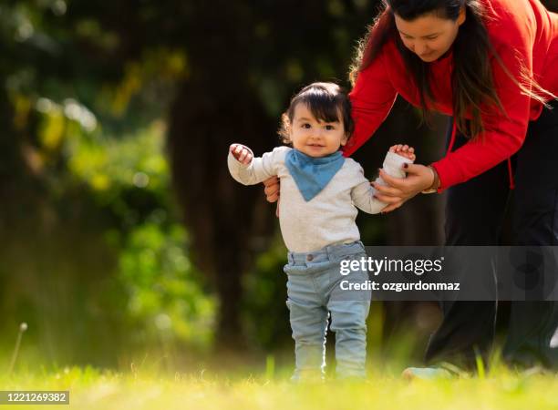 mother helping baby boy to practice walking at the backyard - turkish boy stock pictures, royalty-free photos & images