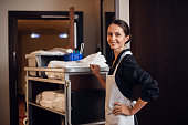 Smiling hotel maid with fresh towels doing housekeeping