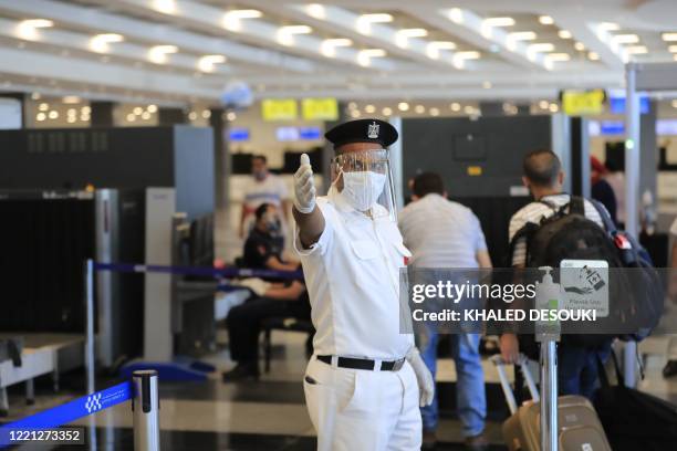 An Egyptian policeman, wearing a protective face shield, signals to passengers at the Sharm el-Sheikh international airport on June 20, 2020.