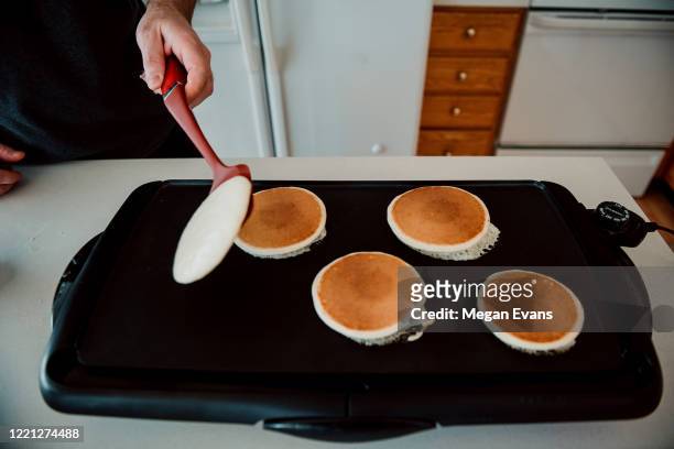 father flipping pancakes on a griddle - griddle stock pictures, royalty-free photos & images