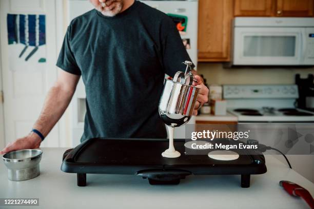 dad pouring pancake batter onto a griddle - griddle stock pictures, royalty-free photos & images