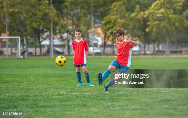 rode trui 14-jarige boy voetballer oefenen schoppen - gypsy of the year competition stockfoto's en -beelden