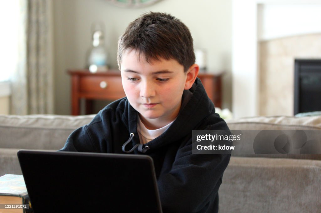 Boy concentrates with laptop at home