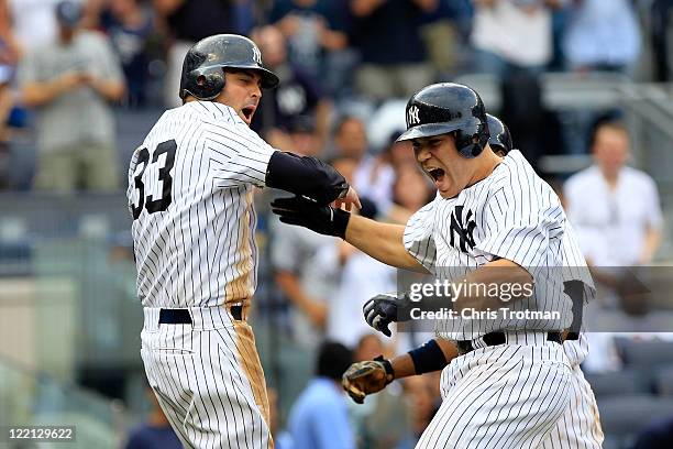 Russell Martin of the New York Yankees is congratulated by teammate Nick Swisher on his grand slam home run in the sixth inning against the Oakland...