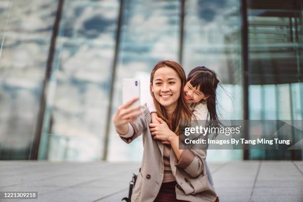 mom & daughter taking selfies joyfully in downtown district - toothy smile family outdoors stock pictures, royalty-free photos & images