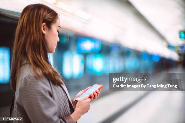 young asian woman using mobile phone while commuting with the train in the city - hong kong mass transit fotografías e imágenes de stock