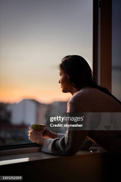 young woman looking through window during coffee time. - woman looking at view stock pictures, royalty-free photos & images