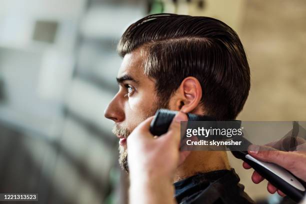 jeune homme ayant une coupe de cheveux au salon de coiffure. - homme coiffure photos et images de collection
