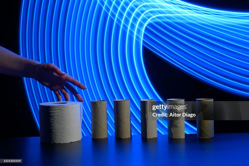 Person´s hand is going to take the last toilet paper. Futuristic curved blue lines in the background.