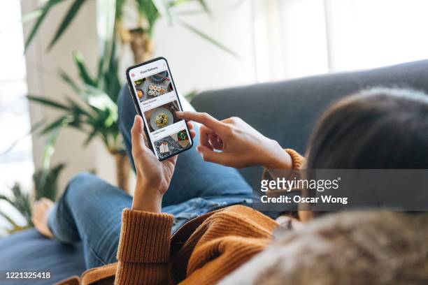 ordering food online at home with smartphone - draagbare informatie apparatuur stockfoto's en -beelden